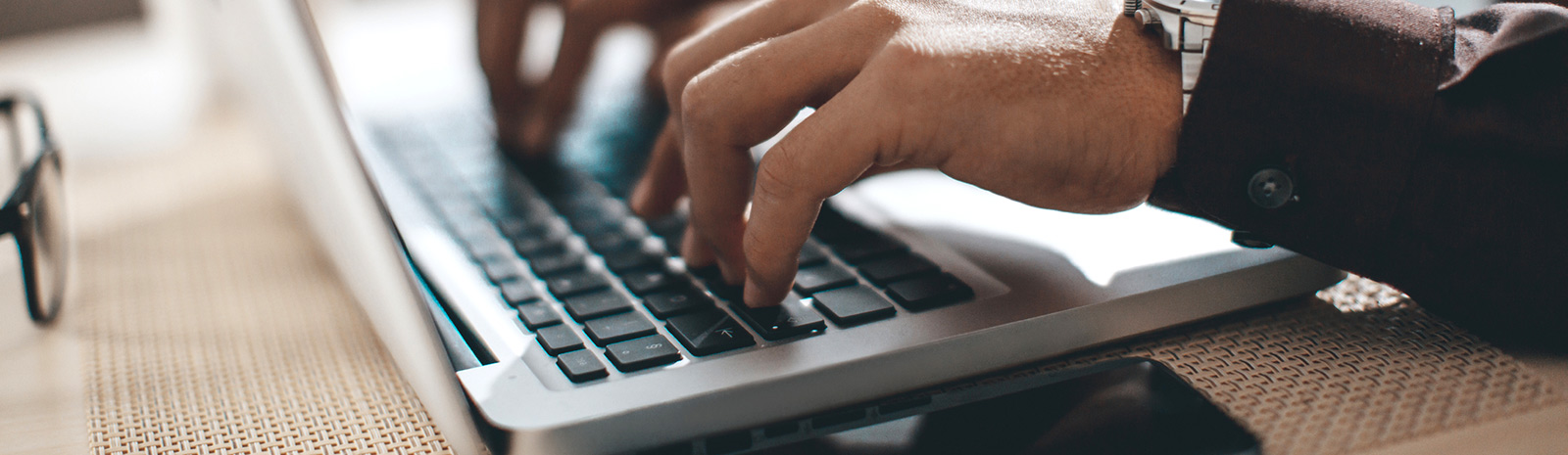 Close up of a person's hands using a laptop keyboard